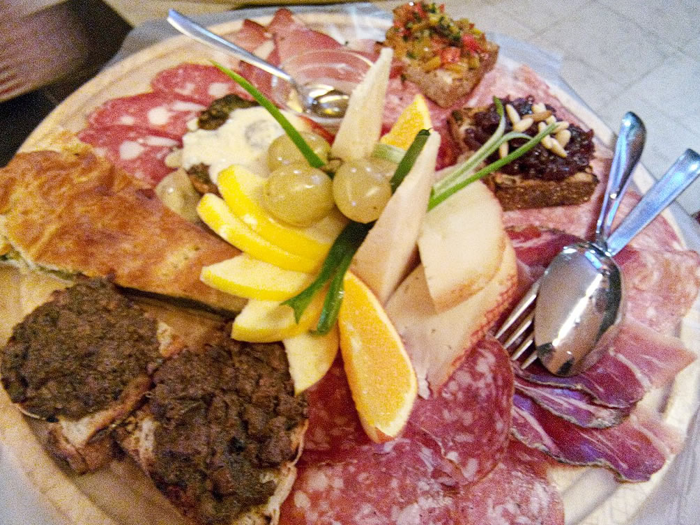 Een snijplank met producten uit Toscane: croutons, fruit, hapjes met groenten, pecorino kaas, vleeswaren.