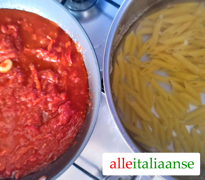 Penne koken en tomatensaus in een andere pan