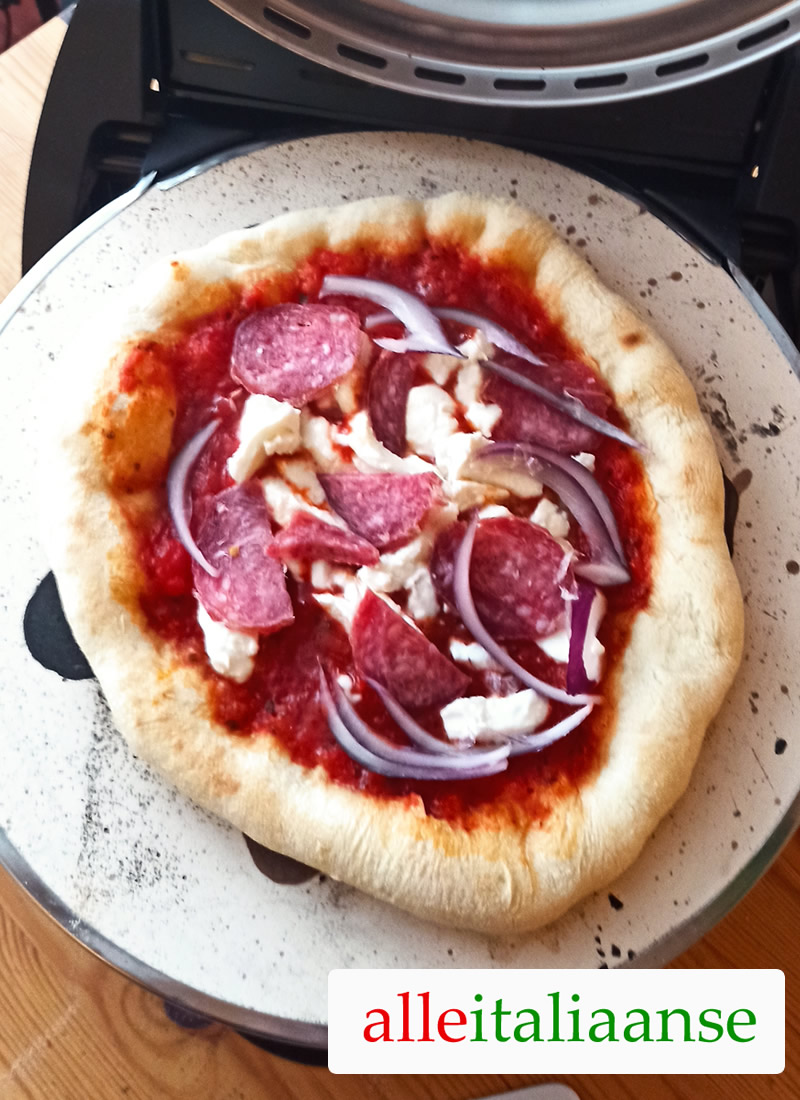 Italiaanse pizza op pizzasteen met salami toppings