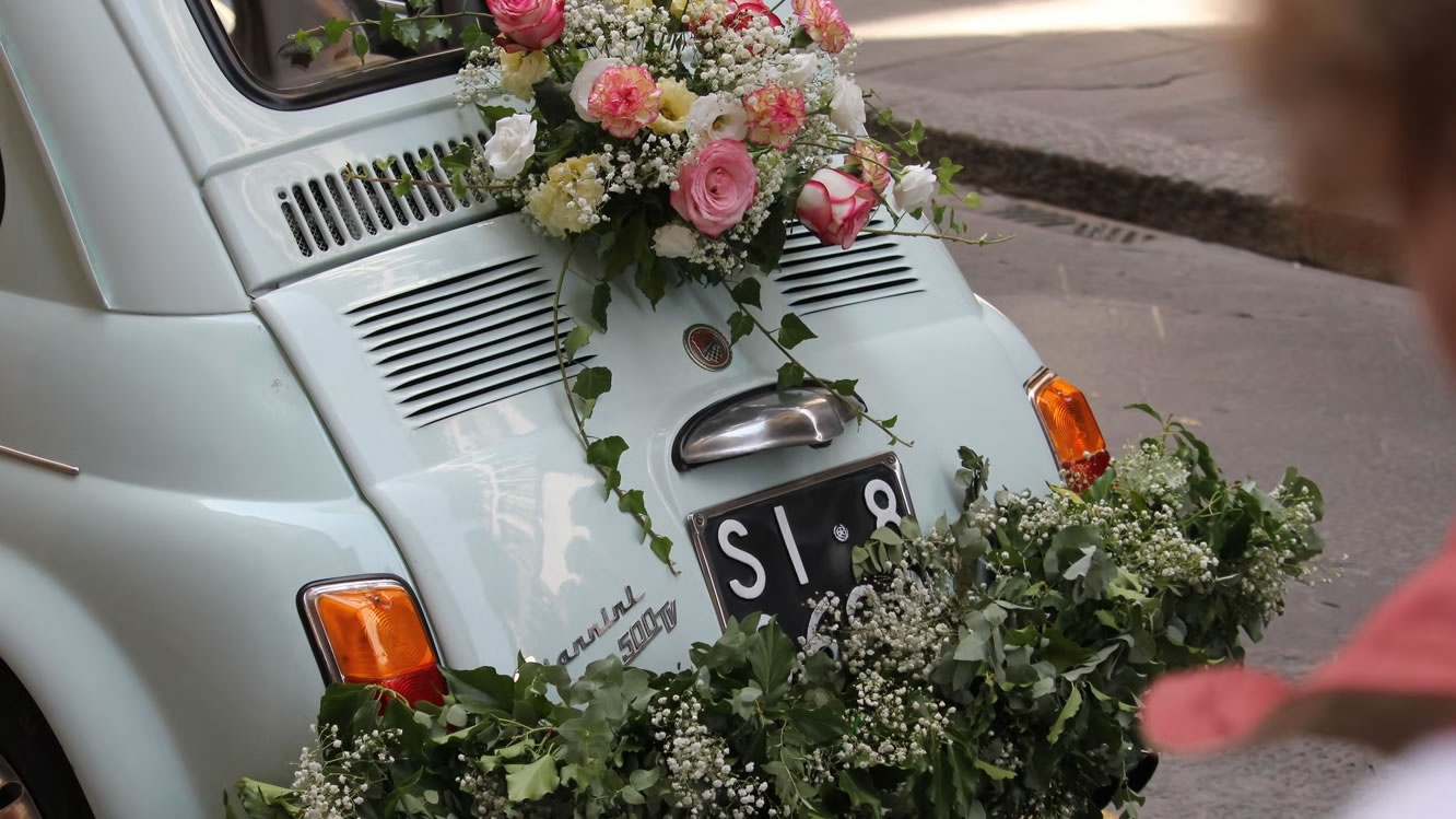 Een fiat 500 met bloemen versierd voor een bruiloft